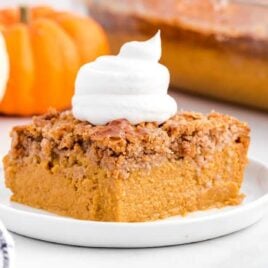 close up shot of a slice of Pumpkin Dump Cake topped with whipped cream on a plate
